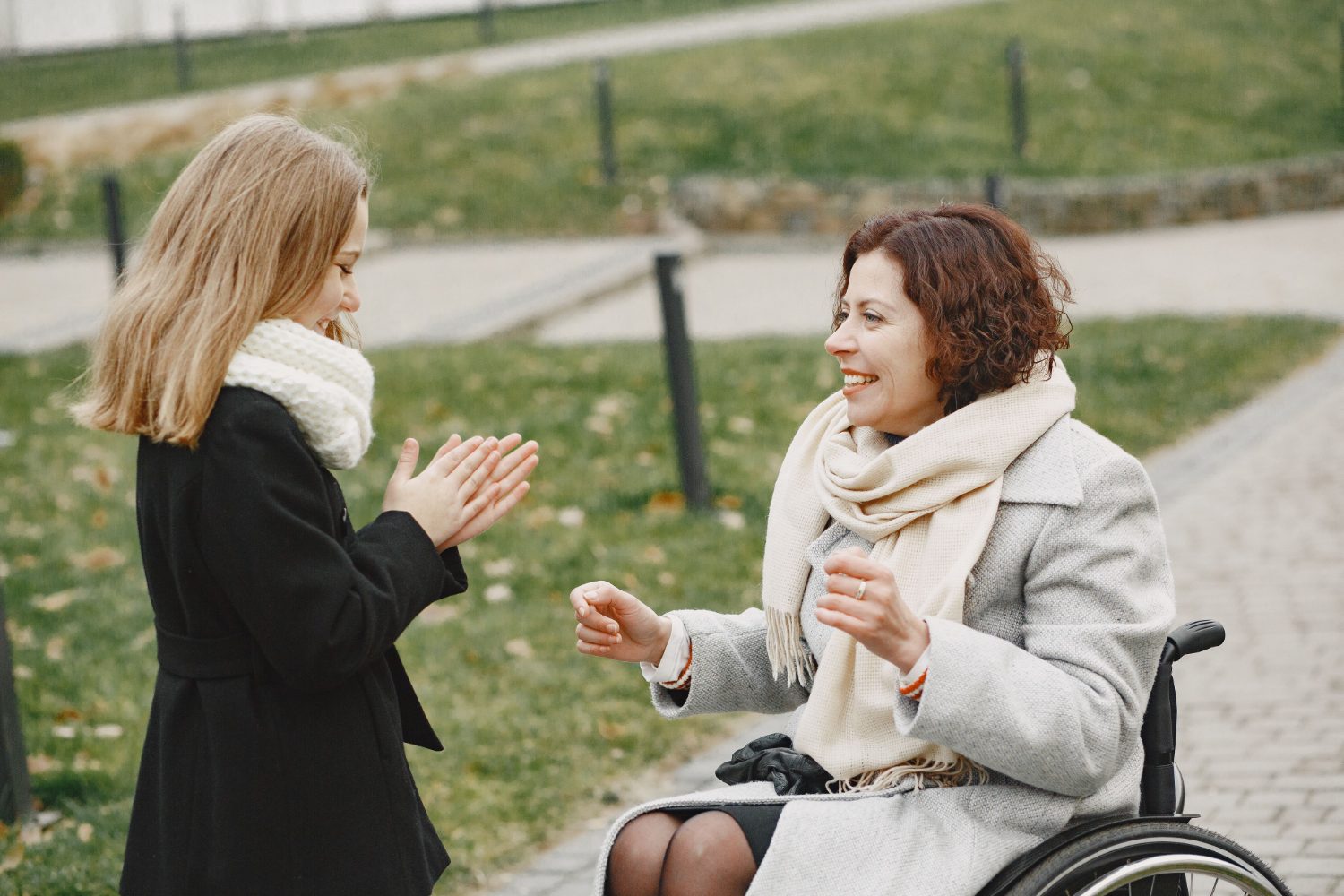 A support worker and a woman in a wheelchair chatting and laughing together in a park
